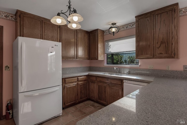 kitchen with decorative light fixtures, an inviting chandelier, a sink, and white appliances
