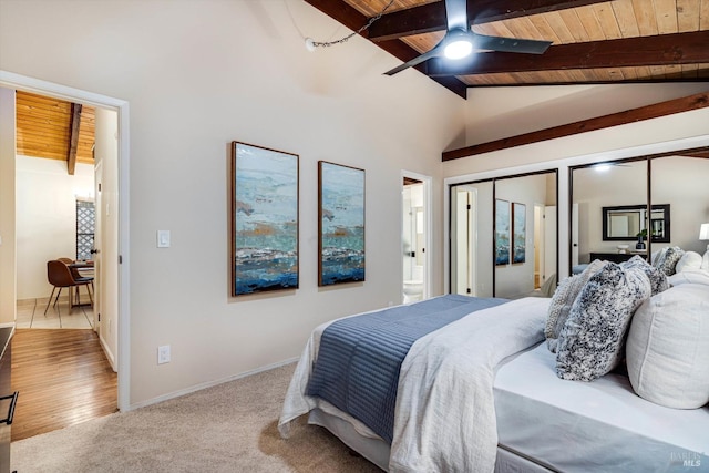 carpeted bedroom with lofted ceiling with beams, baseboards, a ceiling fan, wooden ceiling, and ensuite bath