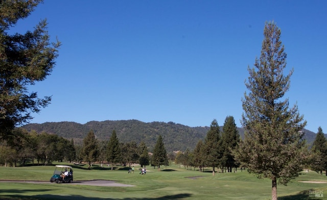 view of property's community with a yard, golf course view, and a mountain view