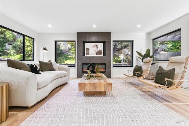 living room with recessed lighting, wood finished floors, and a large fireplace