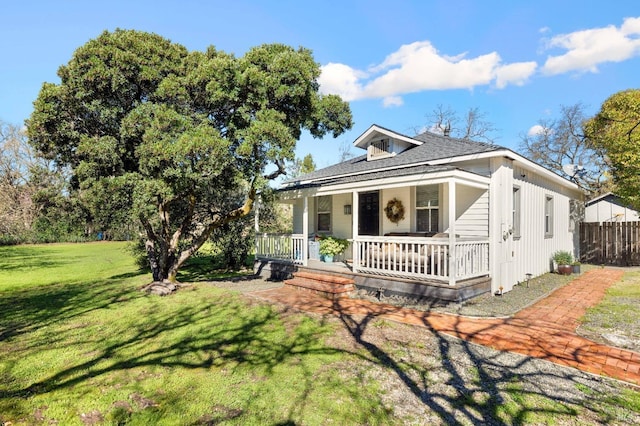 view of front of property with a front lawn, fence, a shingled roof, and covered porch