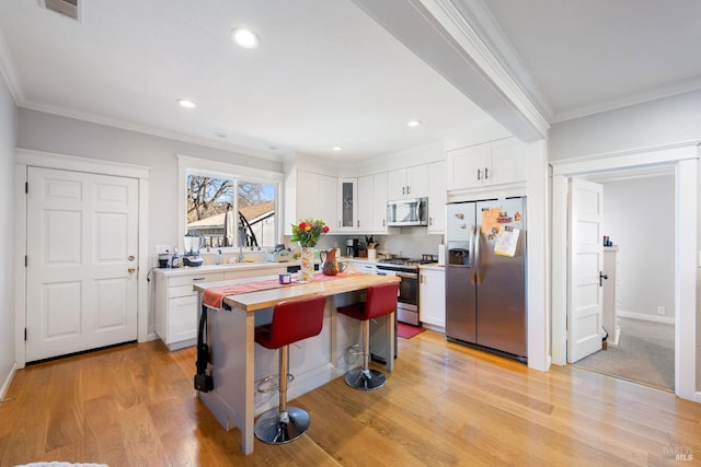 kitchen with stainless steel appliances, a kitchen island, white cabinetry, and glass insert cabinets