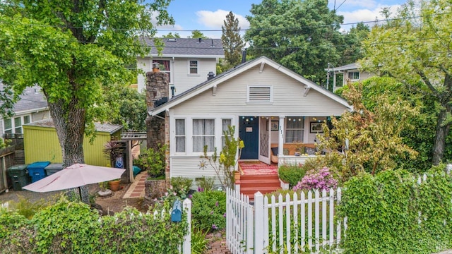 bungalow with a storage shed, fence private yard, covered porch, and an outdoor structure