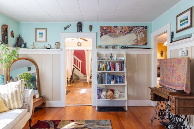 sitting room featuring hardwood / wood-style flooring, crown molding, a ceiling fan, and stairs