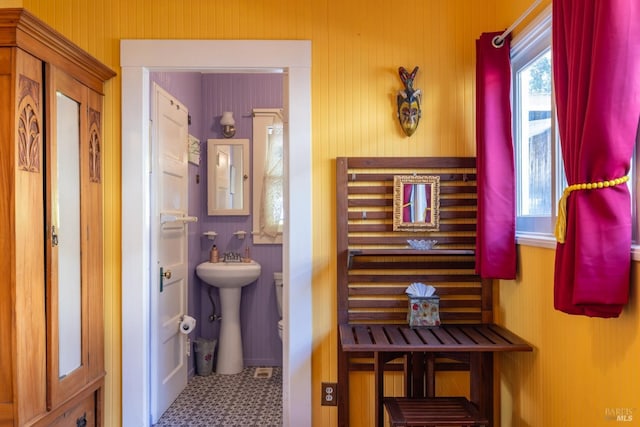 bathroom with tile patterned floors and wood walls