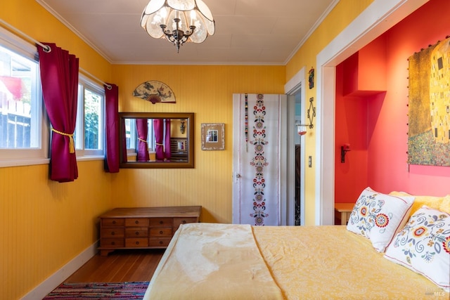 bedroom featuring wood finished floors, crown molding, baseboards, and an inviting chandelier