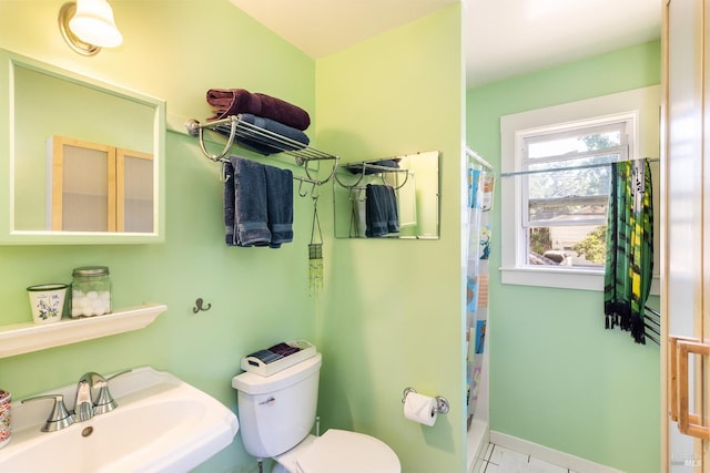 bathroom with toilet, a shower with shower curtain, a sink, and baseboards