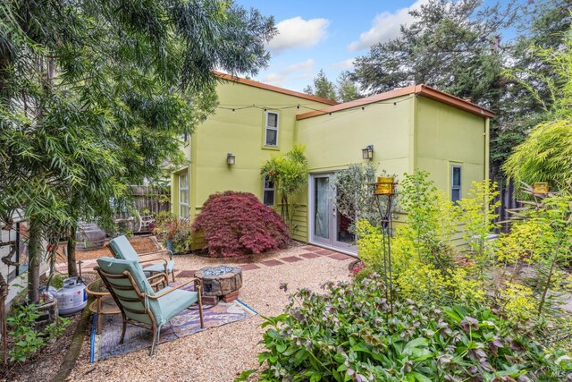 back of house with fence, a patio area, a fire pit, and stucco siding
