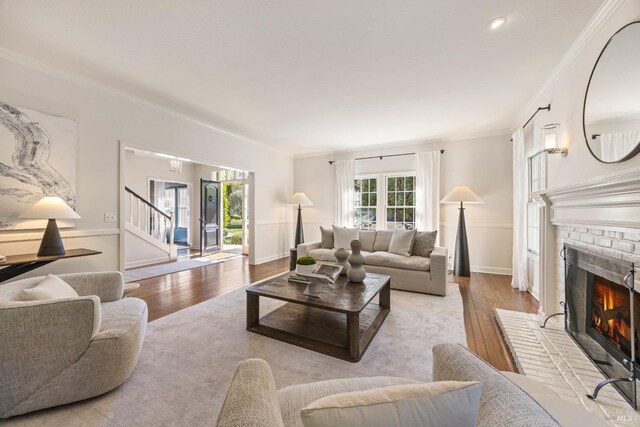 living room with hardwood / wood-style floors, stairs, a fireplace, baseboards, and ornamental molding
