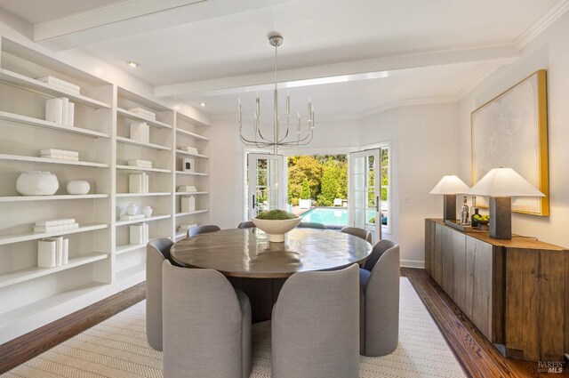 dining area with wood finished floors, crown molding, baseboards, and an inviting chandelier