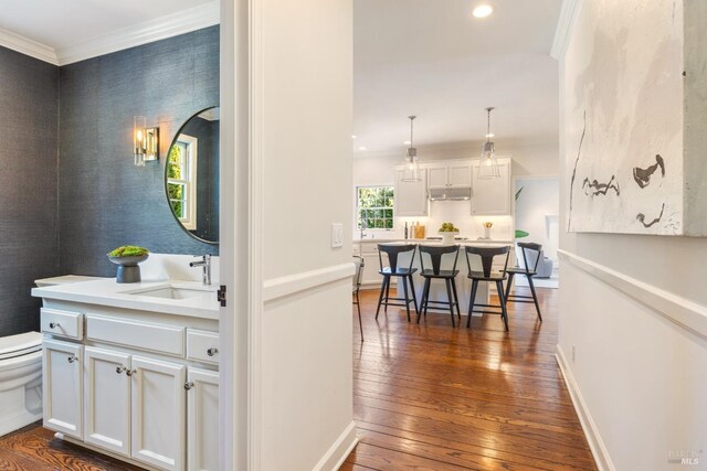 corridor featuring ornamental molding, a sink, dark wood-style floors, and recessed lighting