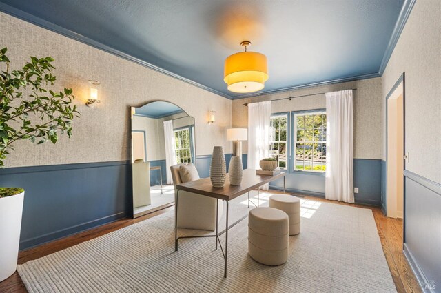 home office with wallpapered walls, wood finished floors, crown molding, and wainscoting