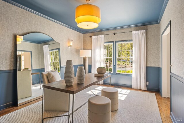 home office featuring crown molding, wood finished floors, wallpapered walls, and a healthy amount of sunlight