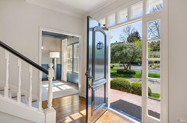 entryway featuring hardwood / wood-style floors, baseboards, stairs, and ornamental molding