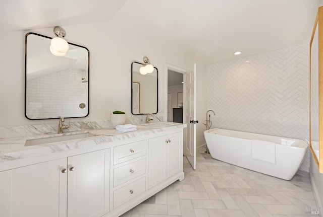 bathroom featuring a freestanding bath, a sink, double vanity, and recessed lighting