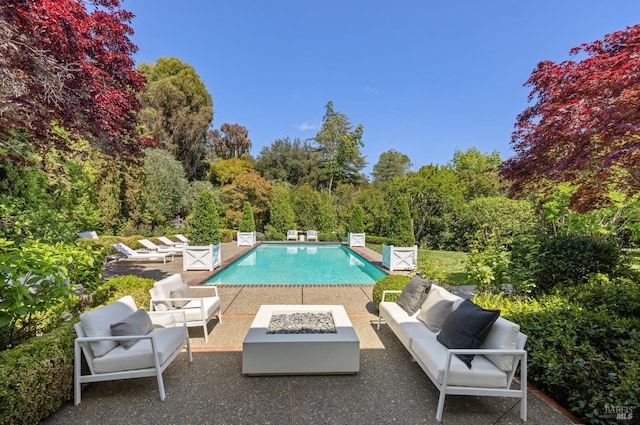 pool with a patio area and an outdoor living space with a fire pit