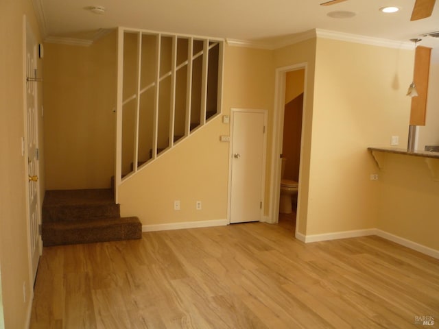 unfurnished living room with baseboards, ornamental molding, wood finished floors, and stairway