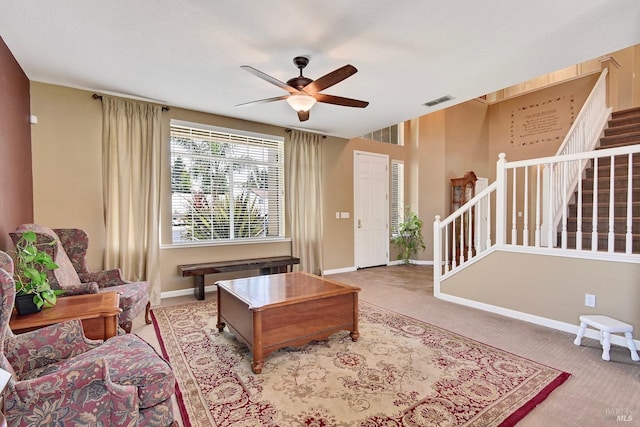 living room with carpet flooring, a ceiling fan, baseboards, and stairway
