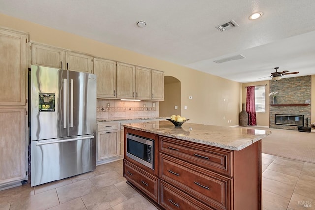kitchen featuring light stone counters, stainless steel appliances, visible vents, light tile patterned floors, and arched walkways