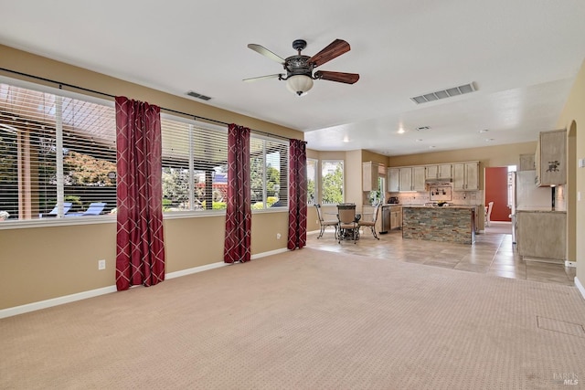 unfurnished living room featuring visible vents, light carpet, baseboards, and ceiling fan