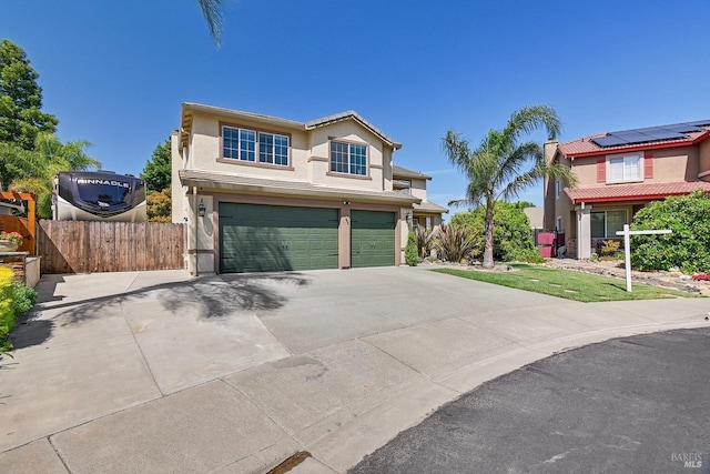 traditional home featuring stucco siding, an attached garage, driveway, and fence