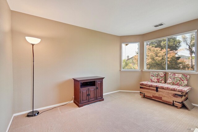sitting room featuring visible vents, baseboards, and light carpet