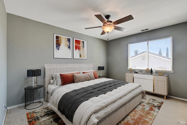 bedroom featuring ceiling fan, visible vents, baseboards, and light carpet