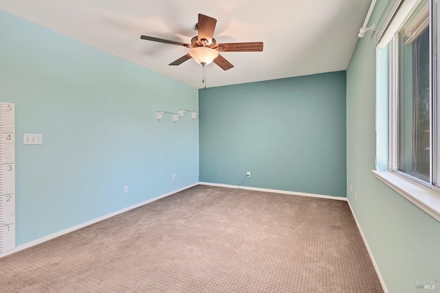 carpeted empty room with ceiling fan and baseboards