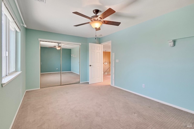 unfurnished bedroom featuring a ceiling fan, carpet floors, a closet, and baseboards
