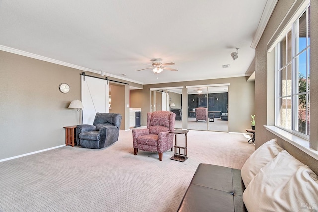 carpeted living room with crown molding, baseboards, ceiling fan, and a barn door
