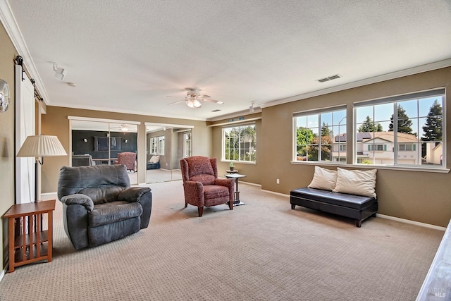carpeted living room with a textured ceiling, baseboards, visible vents, a ceiling fan, and ornamental molding