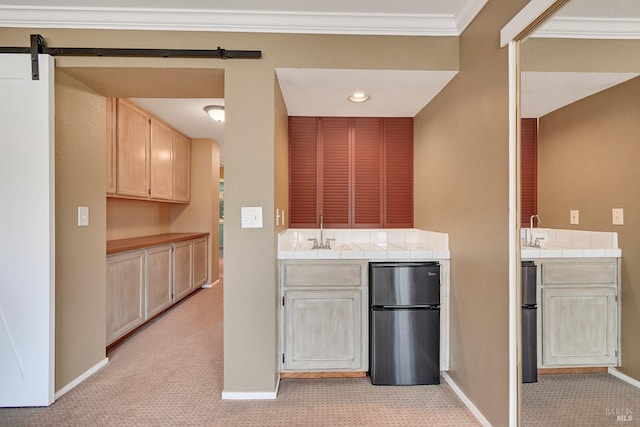 kitchen featuring light brown cabinets, tile counters, freestanding refrigerator, and light colored carpet