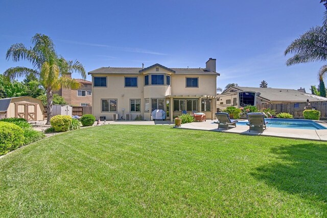 rear view of house featuring a patio area, a chimney, a fenced backyard, an outdoor structure, and a storage unit