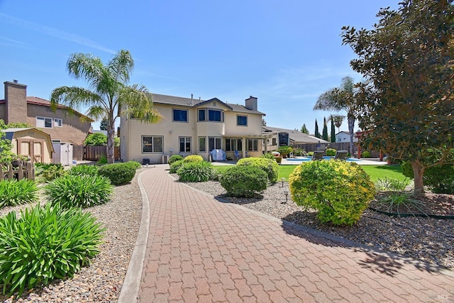 view of property's community with fence, an outdoor structure, a storage shed, and a patio