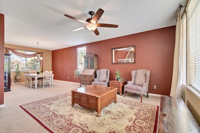 living area with carpet flooring, baseboards, and ceiling fan
