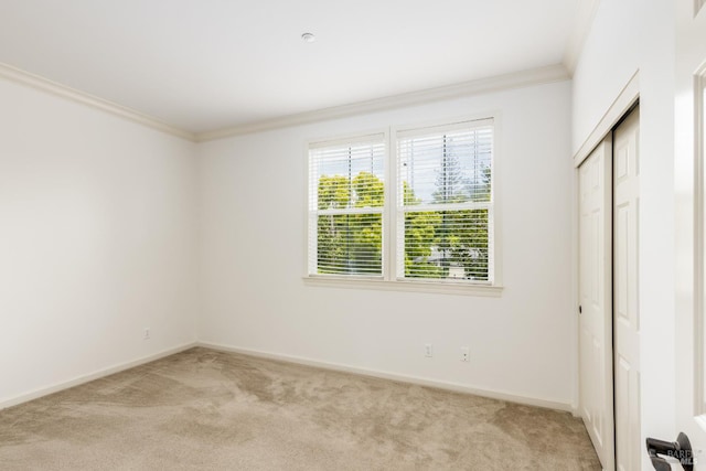 unfurnished bedroom featuring a closet, light carpet, crown molding, and baseboards