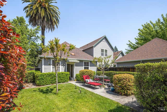 back of property with fence, a yard, a patio, and a shingled roof