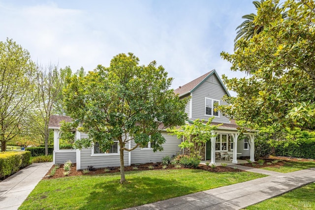 view of front of house with a shingled roof and a front lawn