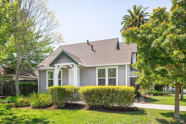 bungalow-style house with a shingled roof, a front lawn, and fence