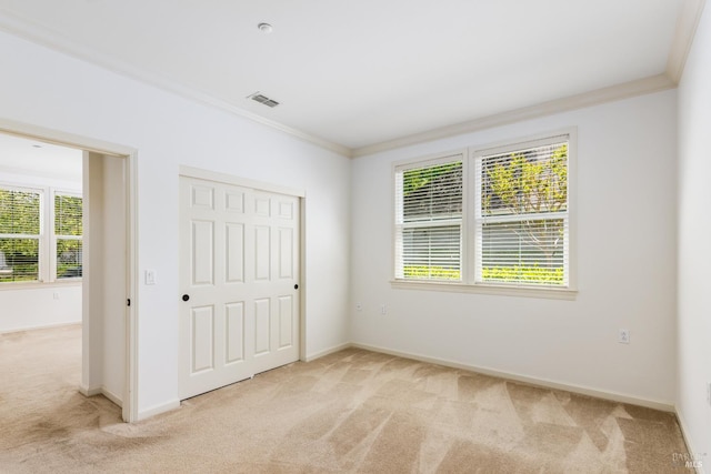 unfurnished bedroom featuring light carpet, visible vents, baseboards, a closet, and crown molding