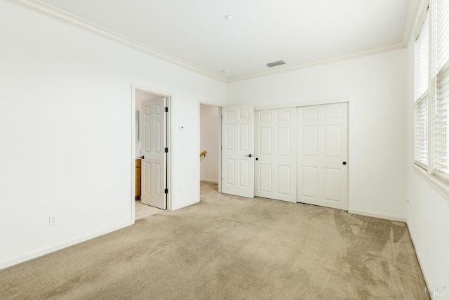 unfurnished bedroom featuring baseboards, visible vents, a closet, crown molding, and carpet floors