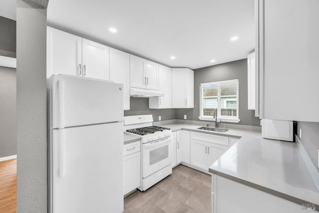 kitchen with white cabinetry, a sink, light countertops, under cabinet range hood, and white appliances