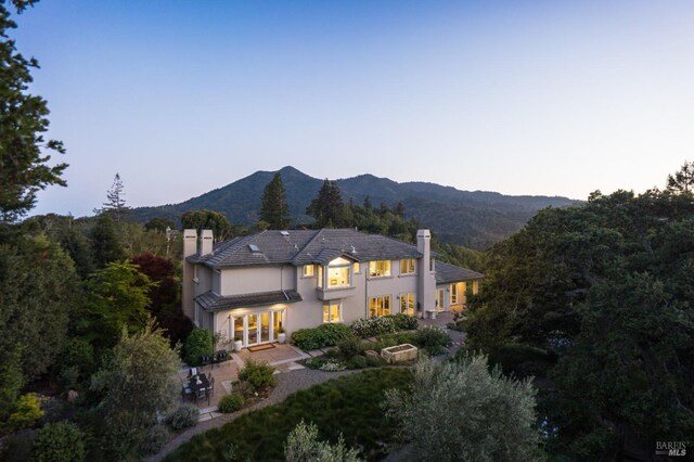 656 Goodhill Rd, Kentfield, CA 94904 - back of property at dusk with french doors, a patio area, a chimney, and a balcony