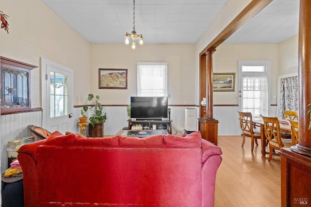 living room with a healthy amount of sunlight, wood finished floors, and decorative columns