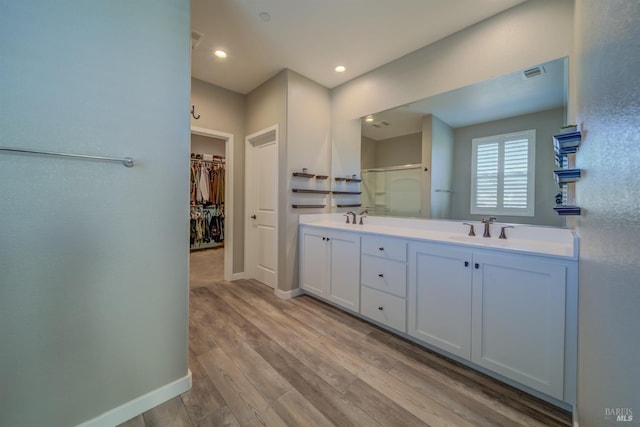 bathroom with a sink, double vanity, baseboards, visible vents, and a stall shower