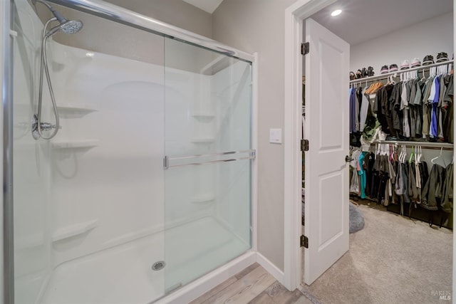 bathroom featuring baseboards, a shower stall, and a walk in closet