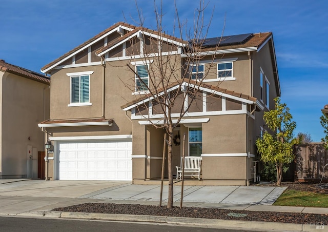 view of front of home featuring a garage, stucco siding, solar panels, and driveway