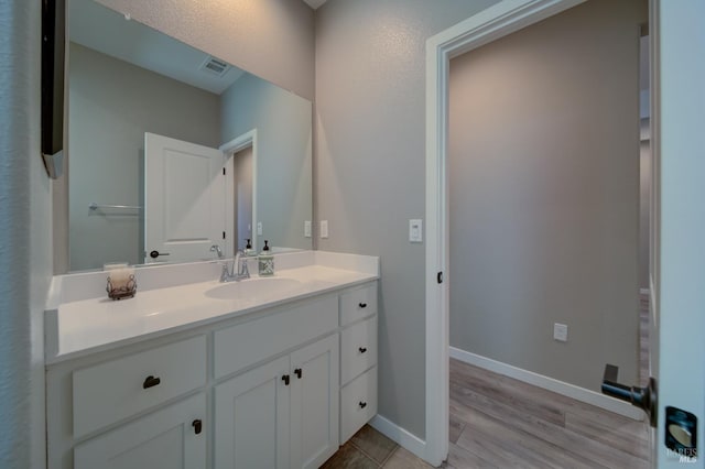 bathroom with vanity, baseboards, wood finished floors, and visible vents