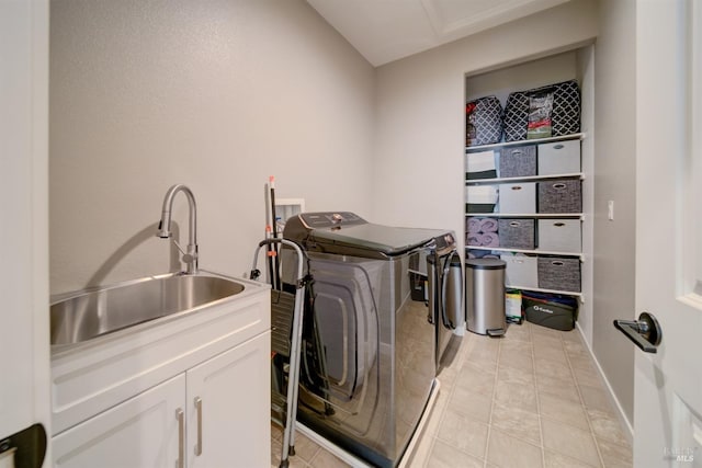 clothes washing area with baseboards, a sink, cabinet space, independent washer and dryer, and light tile patterned floors