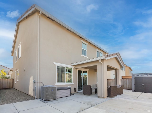 back of house with fence, stucco siding, outdoor lounge area, cooling unit, and a patio